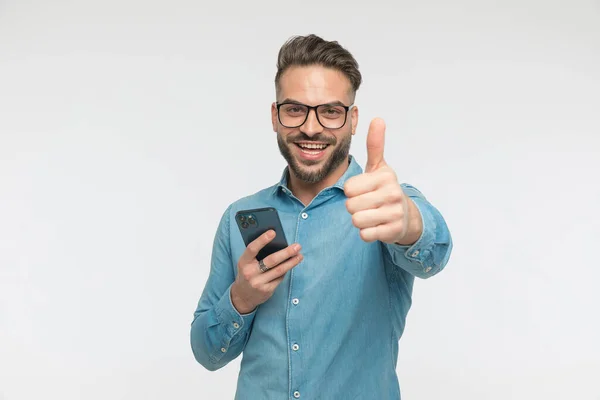남자가 휴대폰으로 메시지를 카메라 앞에서 미소를 짓습니다 — 스톡 사진