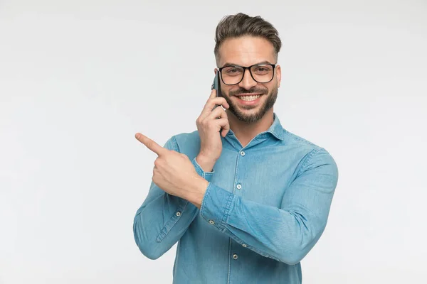 Smiling Casual Man Pointing Side Talking Phone Gray Studio Background — Stock Photo, Image