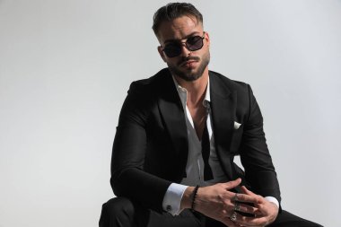 Açık yakalı seksi adam el ele tutuşuyor ve stüdyoda gri arka planda poz veriyor.