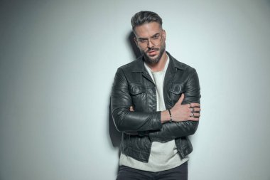 Çok derin ve delici bir bakışla kameraya bakan, gözlük takan ve kollarını kavuşturan seksi, sıradan bir adam. 