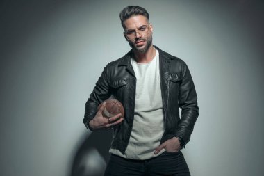 Rugby topu tutan bir manken ve bir eli cebinde. Moda sporu filminde havalı bir görünümü var.