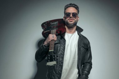 Yakışıklı rockçı elektro gitarını omzunda tutuyor ve erkeksi enerjisi dışarı sızıyor. 