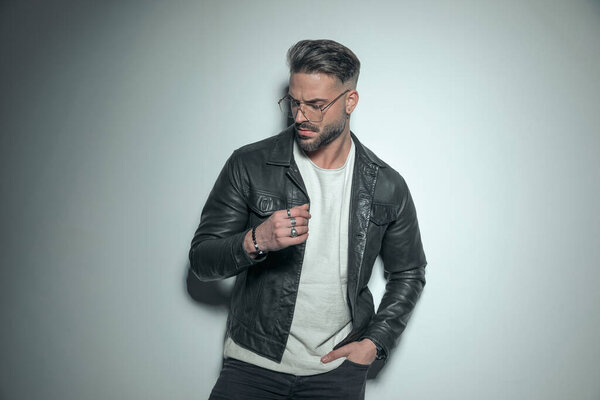 sexy casual guy looking down with a very serious look on his face, holding one hand in pocket in a dramatic fashion picture