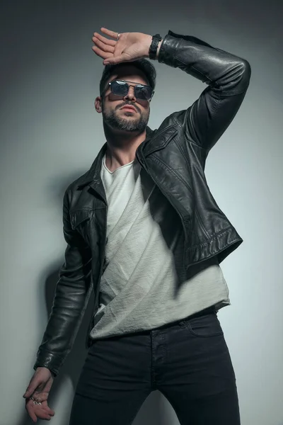 セクシーなカジュアルな男が劇的な クールなサングラスと素敵な革のジャケットを着てファッションポーズ — ストック写真