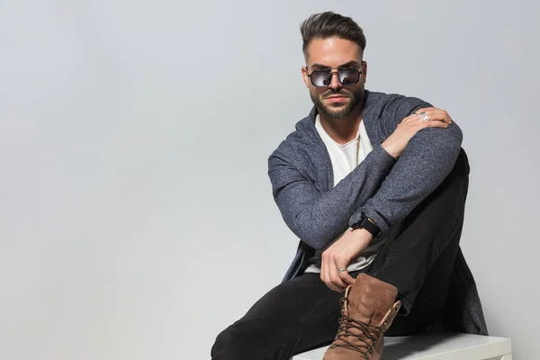 Attractive Seated Man Hoodie Glasses Boots Sitting Leg Holding Elbow — Stock Photo, Image