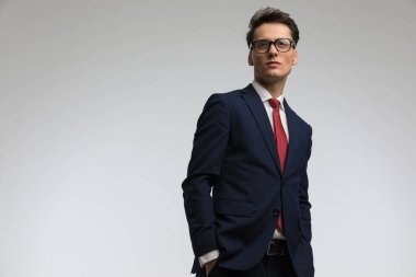 Kendine güvenen iş adamı lacivert takım elbise giyiyor ve kırmızı kravat takıyor. Stüdyoda gri arka planda el ele tutuşuyorlar.