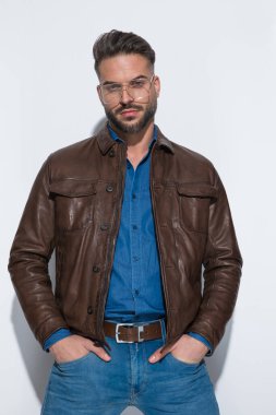 Çekici sıradan bir adam ellerini cebine sokar, gözlük takar ve moda pozu verir.