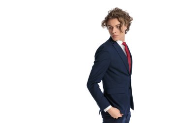 Modrn saç stili olan seksi iş adamının yan görünüşü omuzlarının üstünden bakıyor ve beyaz arka planda pantolon düzenliyor.