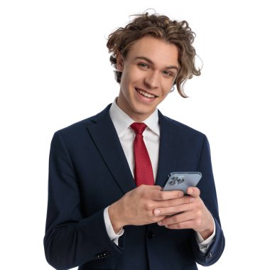 Mutlu iş adamının portresi telefonuna mesaj yazıyor ve stüdyoda beyaz arka planda gülümsüyor.