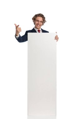 Boş tahtası olan gururlu bir adam. Stüdyoda beyaz arkaplanda gülümseyip poz veriyor.