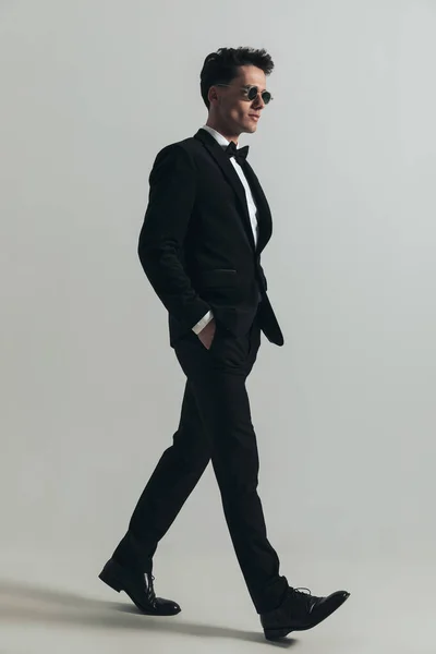 側ビューのセクシーなラテン人で現代的なスタイルの歩行で手でポケットに灰色の背景の前にスタジオ — ストック写真