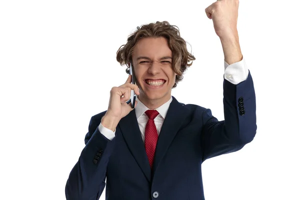 興奮したビジネスマンが電話で語り 空中で拳を握り スタジオの白い背景の前で勝利を祝う姿 — ストック写真