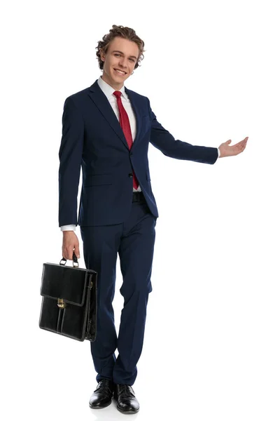 Fier Jeune Homme Costume Élégant Avec Valise Invitant Présentant Côté — Photo