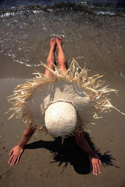 Meisje op een tropisch strand met hoed — Stockfoto
