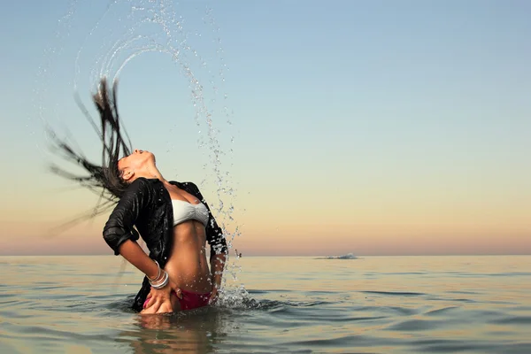 Девушка брызгает морскую воду своими волосами — стоковое фото