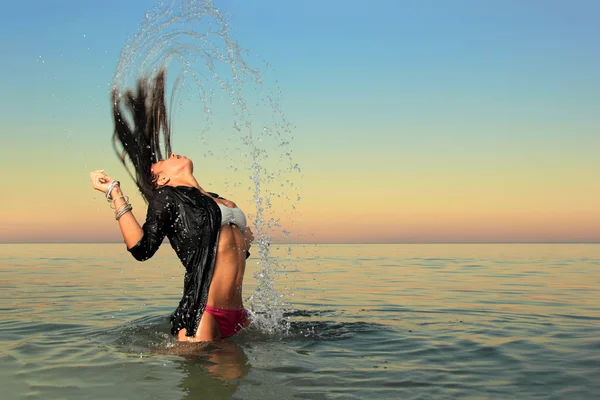 Chica salpicando el agua de mar con su pelo — Foto de Stock