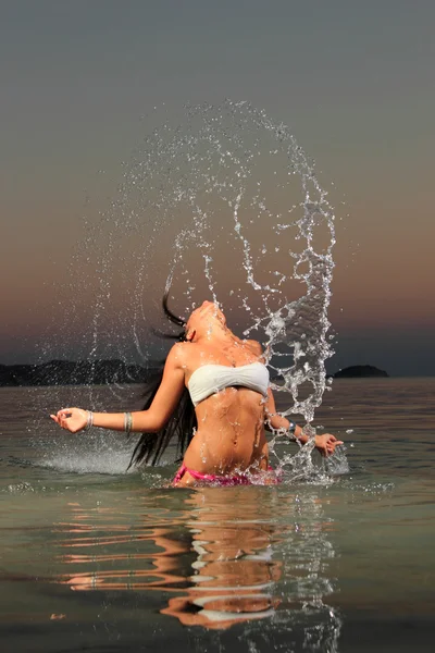 Chica salpicando el agua de mar con su pelo — Foto de Stock