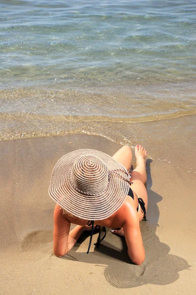 Meisje op een tropisch strand met hoed — Stockfoto