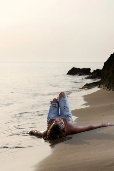 Mooie jonge sexy mode model in spijkerbroek door de zee — Stockfoto