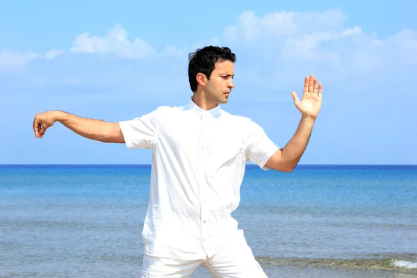 Красивый мужчина на пляже медитирует — стоковое фото