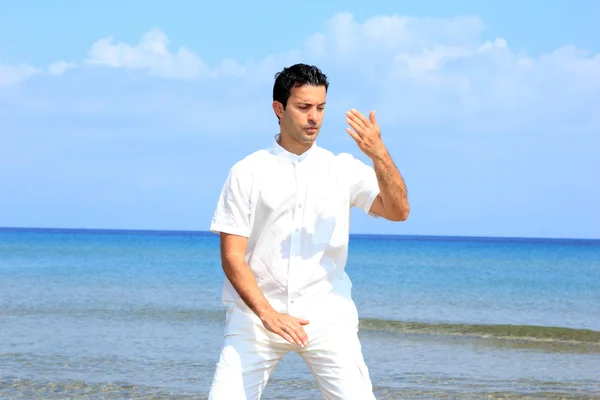 Knappe man op het strand mediteren — Stockfoto