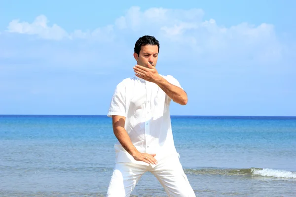 Stilig man på stranden mediterar — Stockfoto