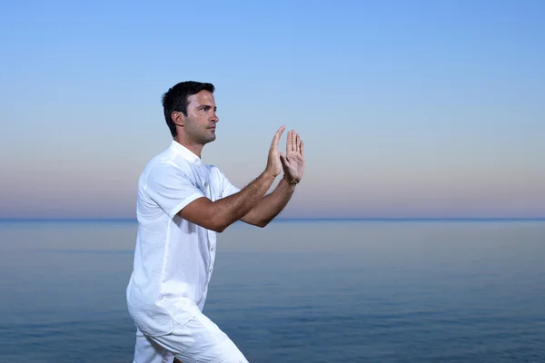 Knappe man op het strand mediteren - tai chi — Stockfoto