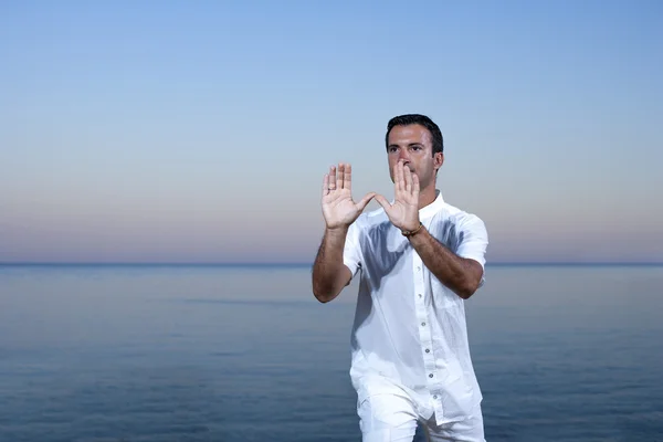 Stilig man på stranden mediterar - tai chi — Stockfoto