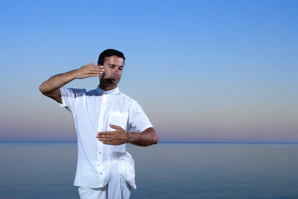 Knappe man op het strand mediteren - tai chi — Stockfoto