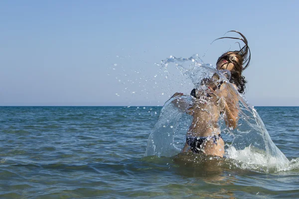 Brunette dans l'eau agitant les cheveux — Photo