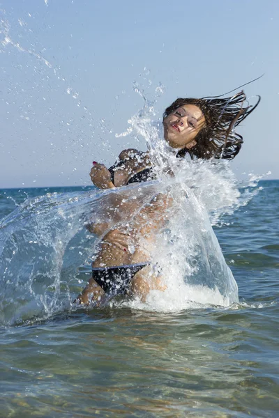 Brunett i vattnet viftande hår — Stockfoto