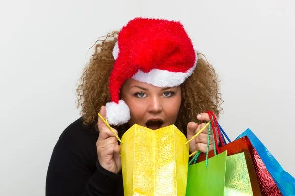Молодая женщина в шляпе Санта-Клауса, держащая в руках шопинг — стоковое фото