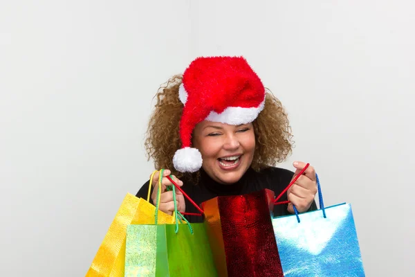 Молодая женщина в шляпе Санта-Клауса, держащая в руках шопинг — стоковое фото