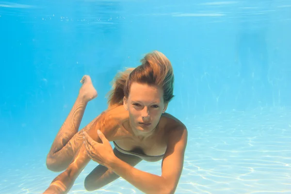 Mujer joven nadando bajo el agua en la piscina —  Fotos de Stock