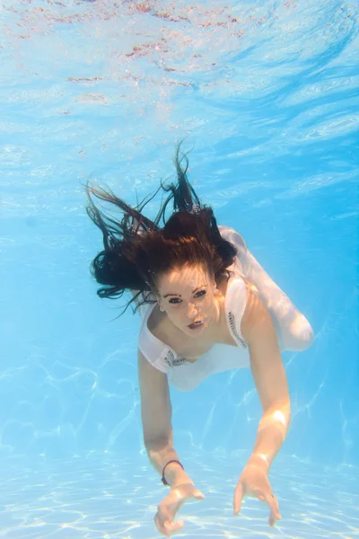 Женщина в белом платье под водой в бассейне — стоковое фото