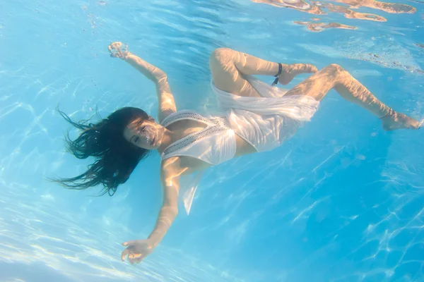 Vrouw in een witte jurk onderwater in zwembad — Stockfoto