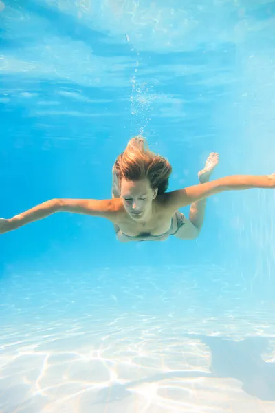 Mujer joven nadando bajo el agua en la piscina —  Fotos de Stock