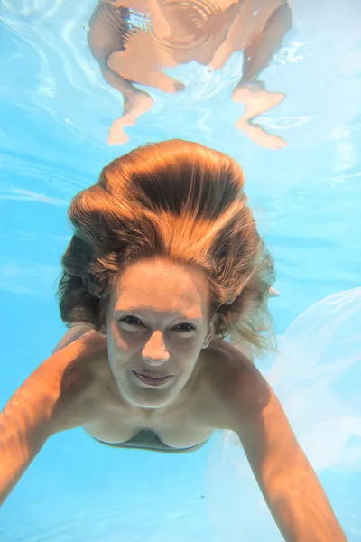 Mujer joven nadando bajo el agua en la piscina —  Fotos de Stock