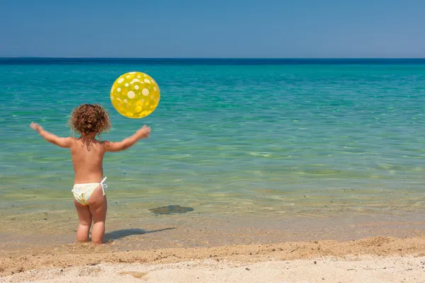 Petite fille jouer avec une balle sur la plage — Photo