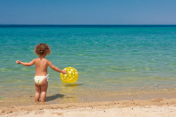 Holčička hraje s míčem na pláži — Stock fotografie