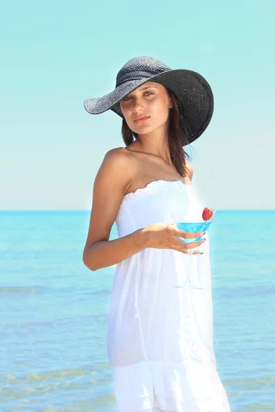 Jonge vrouw op het strand met cocktail — Stockfoto