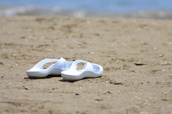 Beach sandals or tongs on a sandy beach — Stock Photo, Image