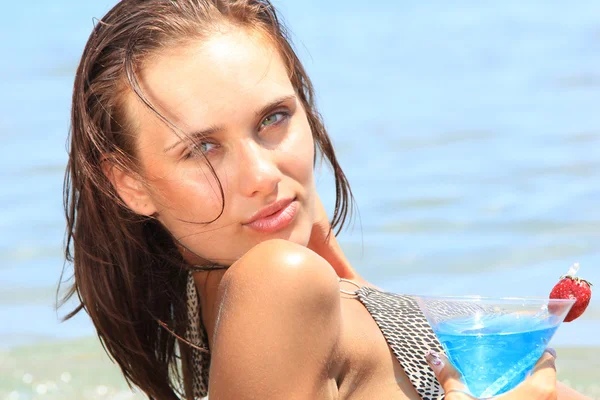 Jonge vrouw op het strand met cocktail — Stockfoto