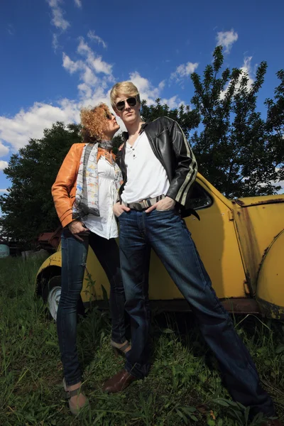 Ein junges Paar auf einem alten Auto in einem Feld — Stockfoto
