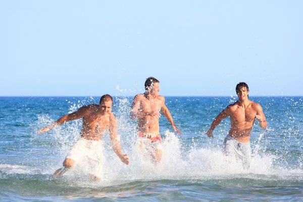 Tre unga män avkopplande på stranden — Stockfoto