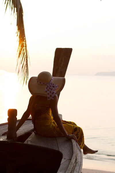 Женщина в саронге на длинной хвостовой лодке на рассвете — стоковое фото