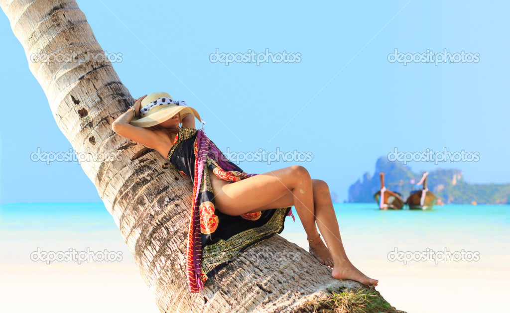 Woman sitting on a coconut tree on Phi Phi