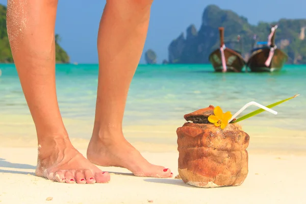 Coconut cocktail with drinking straw and woman's legs — Stock Photo, Image