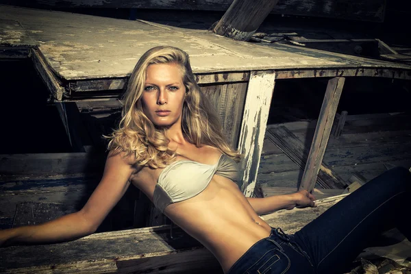 Mujer rubia posando frente a un viejo barco de madera naufragado —  Fotos de Stock