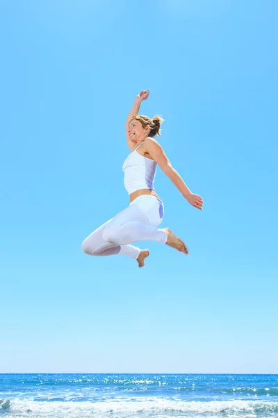 Vrouw springen op het strand — Stockfoto